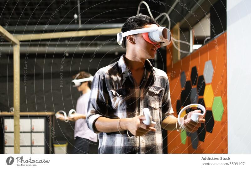 Side view of young excited man is engaged in a virtual reality game wearing a VR headset and using controllers technology vr goggles gadget entertainment