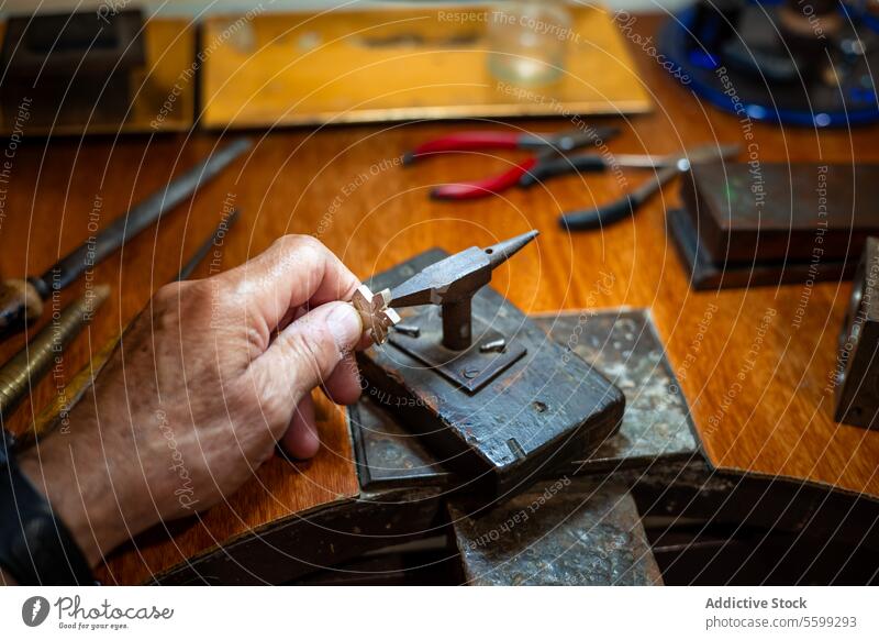 Goldsmith creating and repairing in his crafting gold jewelry workshop with an anvil. Jeweler working in a silver jewel. burin close up craftsman design