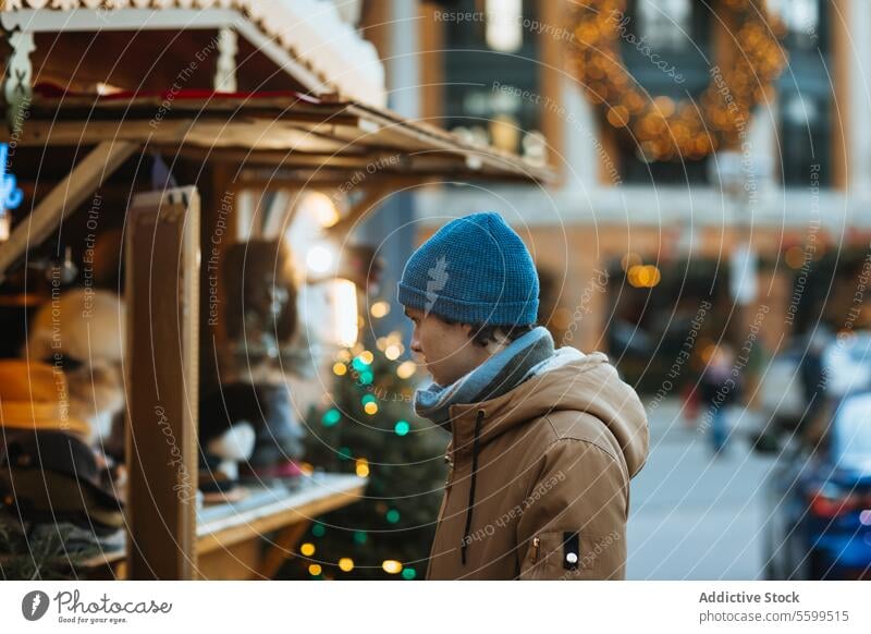 Man Shopping at a Christmas Market Stall in Quebec, Canada man shopping christmas market stall winter outdoor festive decoration beanie coat holiday season cold