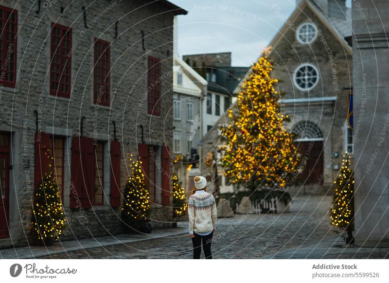 Woman enjoying holiday lights in historic district in Quebec, Canada woman quebec christmas tree back view cobblestone street old town decoration festive winter