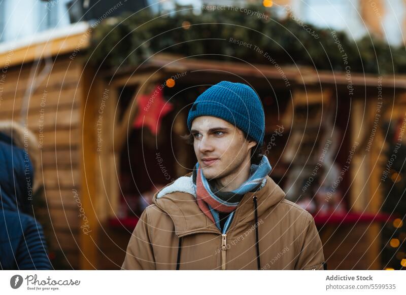 Young man exploring a festive outdoor Christmas market in Quebec, Canada young christmas beanie jacket holiday decoration wooden stall christmas market season
