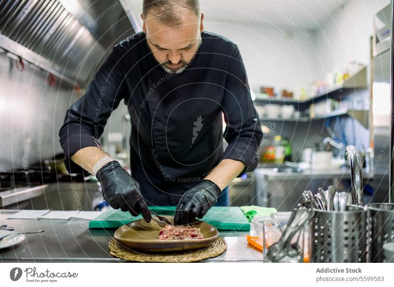 Male serving meat on plate in restaurant kitchen chef man serve cook cut roast beef prepare male glove dish serious food professional meal culinary work beard