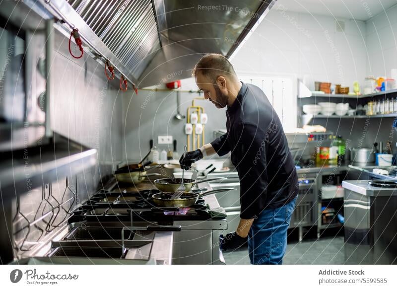 Male chef cooking on frying pan in kitchen man restaurant food professional work culinary gas prepare job dish occupation meal burner serious tasty beard male