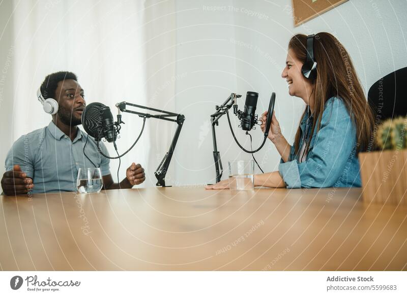 Multiethnic colleagues recording podcast together coworker headphones microphone talk speak broadcast multiethnic multiracial diverse black african american