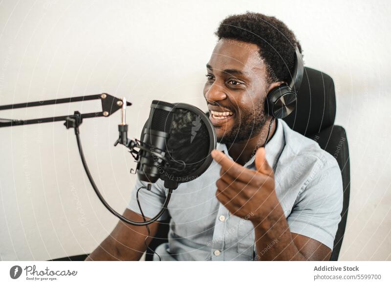 Delighted black man recording podcast and talking in mic radio host microphone headphones positive broadcast male ethnic african american studio delight audio