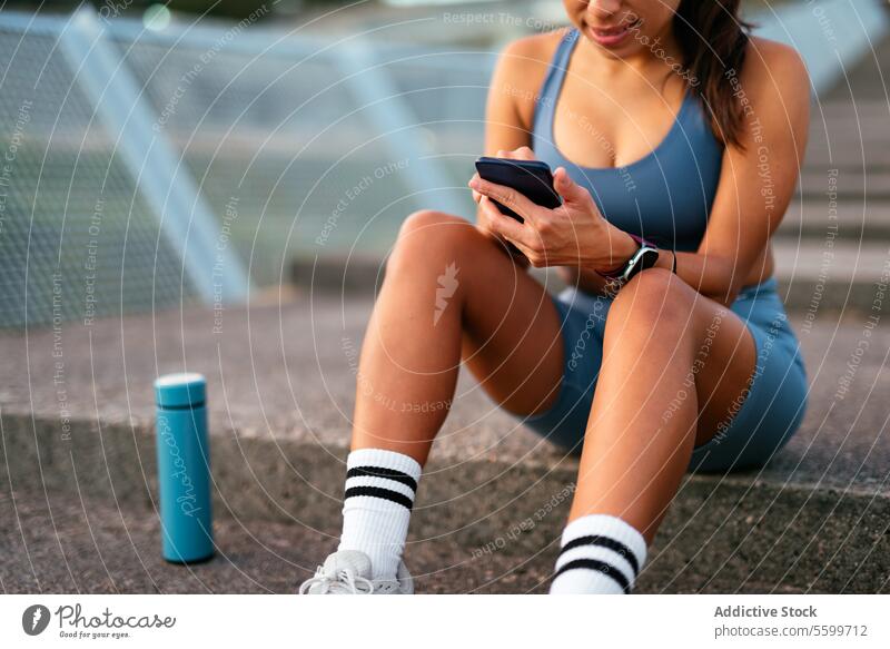 Active lifestyle concept with a Latin American woman using phone latin american smartphone workout break steps water bottle active sitting fitness technology