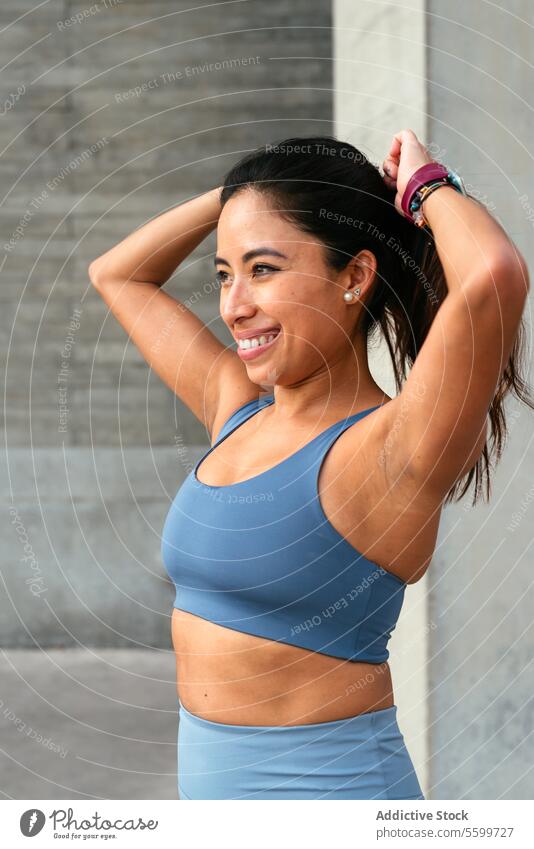 Joyful latin american woman enjoying a fitness break smile workout sportswear tying hair happy active exercise health wellbeing lifestyle leisure sports outfit