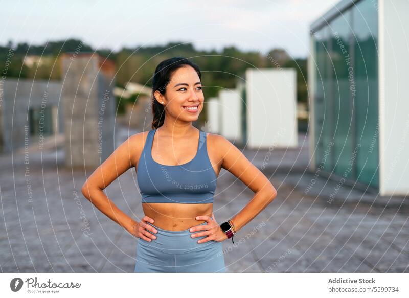 Confident Latina athlete taking a break outdoors woman latina smile confident workout gear exercise session fitness active lifestyle health wellness sportswear
