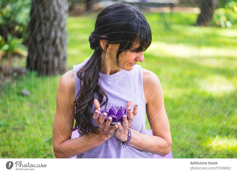Mid adult woman holding holding a purple glass lotus. Yoga and meditation concept. aquatic backyard balance beautiful beauty calm calmness decoration exotic