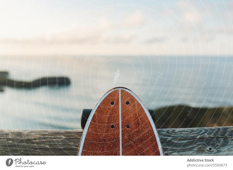 Surf skate leaning on wooden railing against blurred beach skateboard longboard surf sport sea summer outdoors sunset no people nobody lifestyle leisure youth
