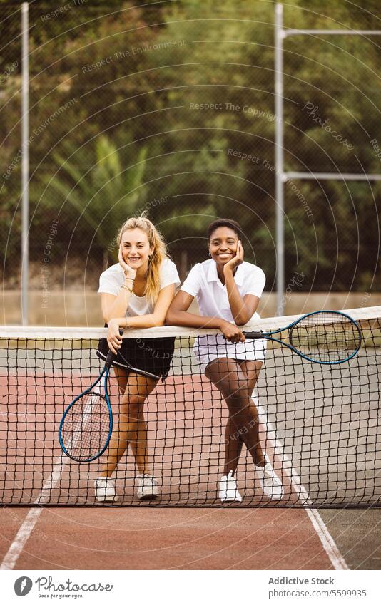 Portrait of two young women on a tennis court active lifestyle activity amateur athlete ball beautiful beautiful women cheerful competition diversity enjoyment