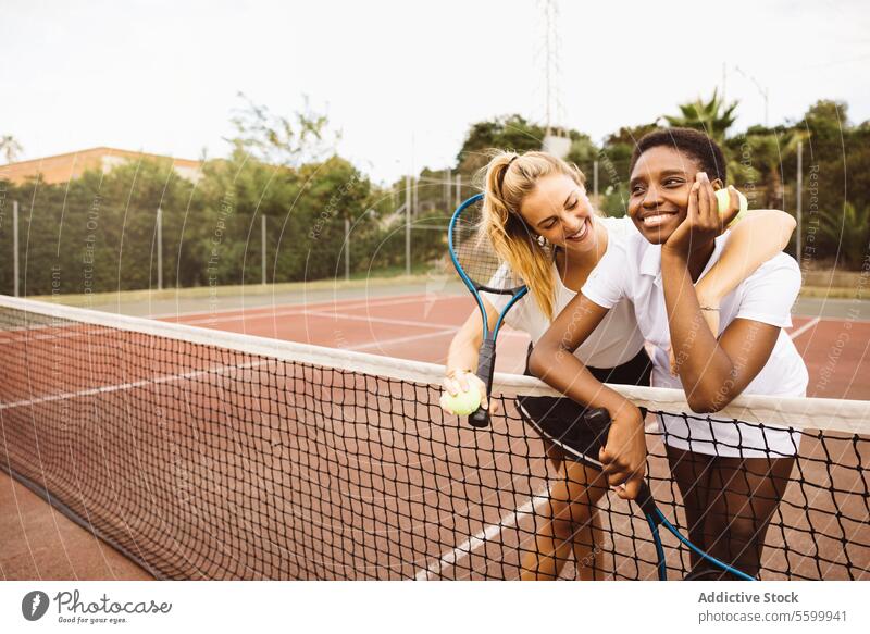 Portrait of two young women on a tennis court active lifestyle activity amateur athlete ball beautiful beautiful women cheerful competition diversity enjoyment