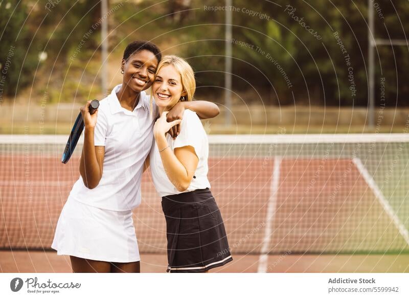 Portrait of two happy women in a tennis court active lifestyle activity amateur athlete ball beautiful beautiful women cheerful competition diversity enjoyment