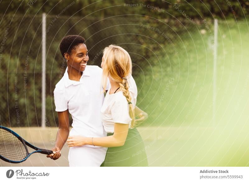 Portrait of two happy women in a tennis court active lifestyle activity amateur athlete ball beautiful beautiful women cheerful competition diversity enjoyment