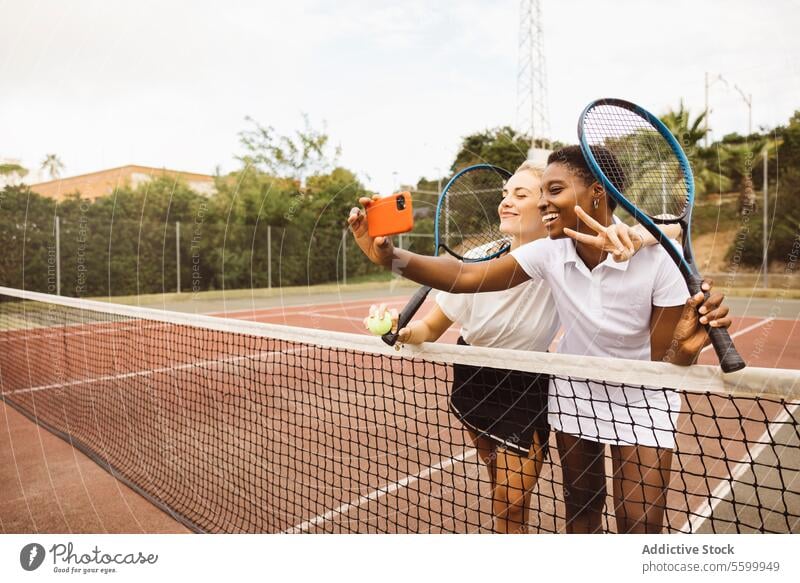 Portrait of two young women on a tennis court active lifestyle amateur athlete beautiful beautiful women cheerful competition diversity enjoyment exercise