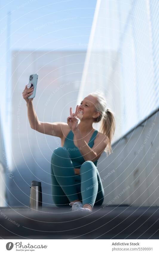 Active senior woman taking a selfie during workout break active mature exercise outdoor health technology fit sport attire cheerful lifestyle wellness fitness