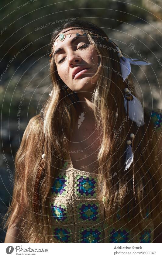 Bohemian woman with feathered headband tilt sunlight bohemian dress colorful embroidery style fashion nature outdoor summer elegant young female adult beauty