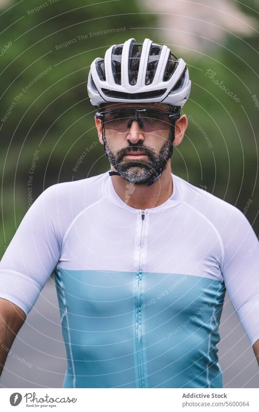 Cyclist portrait cyclist helmet sunglasses jersey blue white serious male athletic outdoor fitness sport gear safety concentration ride health lifestyle