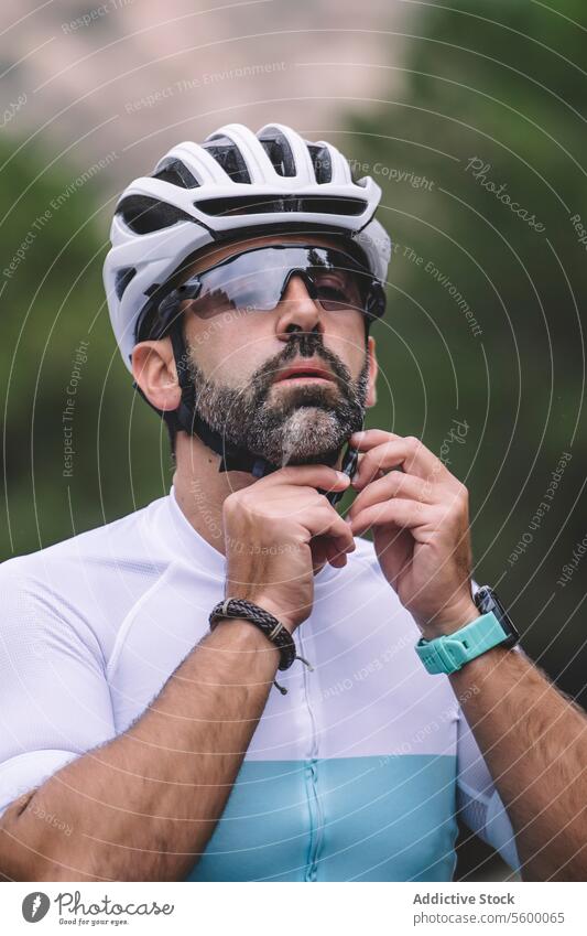 Cyclist adjusting helmet man cyclist sunglasses adjustment mountain jersey white blue portrait outdoor sport gear safety male preparation fitness nature