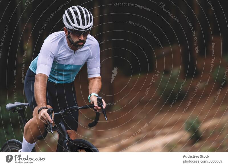 Cyclist on forest turn cyclist bicycle jersey white teal helmet concentration outdoor sport road fitness nature tree ride male athletic gear wheel handlebar