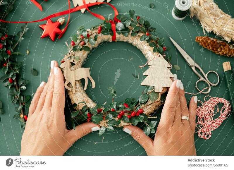 Crop hand of unrecognizable woman with decorative Christmas decorations christmas wreath person ribbon new year xmas tradition festive red celebrate holiday