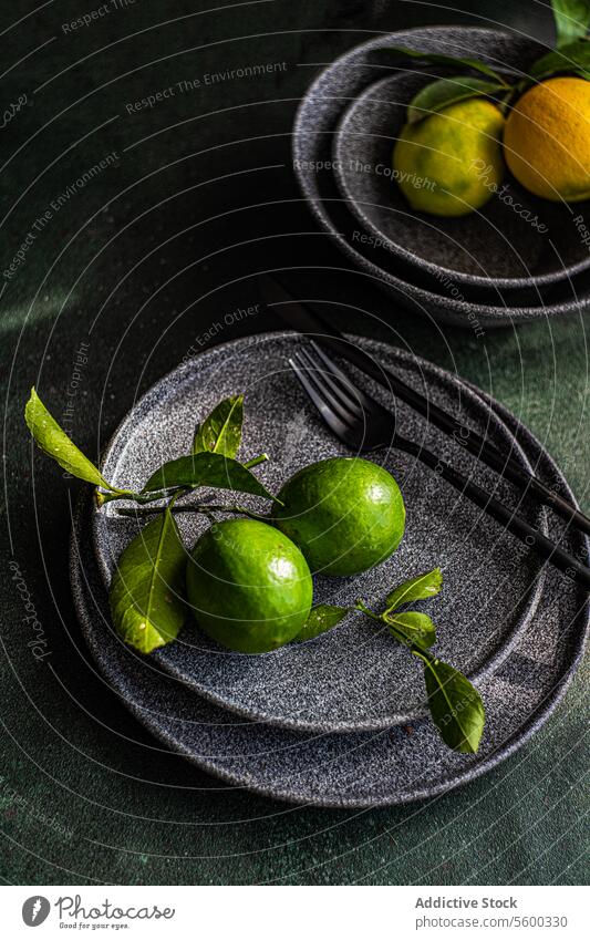 Fresh limes on dark plate with elegant presentation green ceramic fork background soft lighting fresh fruit citrus tableware food healthy vitamin c organic