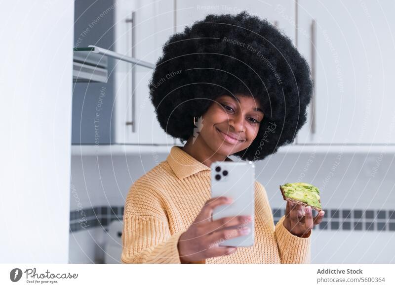 Smiling black female taking selfie with toast woman breakfast healthy lifestyle kitchen smartphone self portrait avocado using morning african american afro