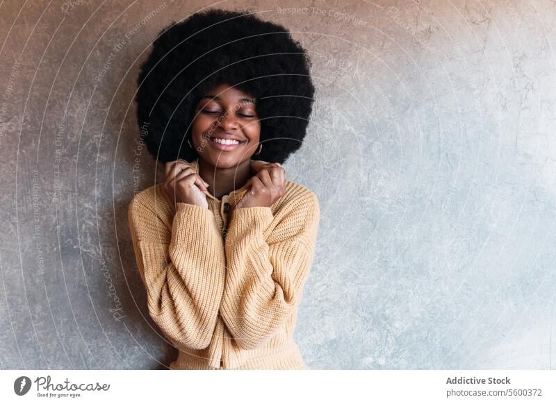 Smiling black woman with closed eyes afro smile eyes closed cheerful sweater individuality personality happy appearance female african american hairstyle young
