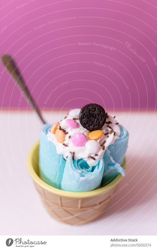 Close up of a blue rolled ice cream decorated with chocolates, cream and a cookie topping spoon bubble tub milk chips yogurt white preparation shop parlor