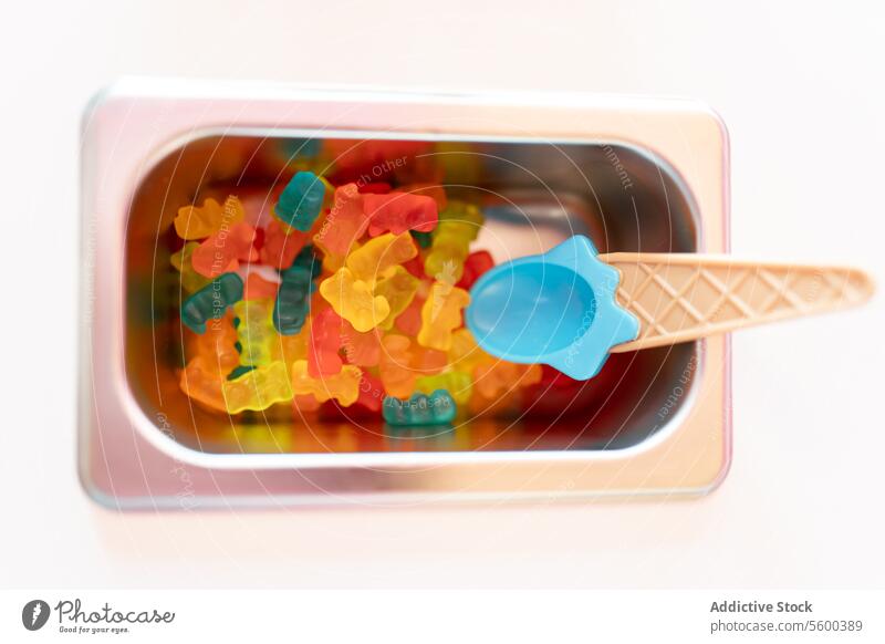 Close up photo of a metal tray filled with teddy bear gummy toppings on an ice cream parlor counter steel rolled colorful preparation shop spoon handmade