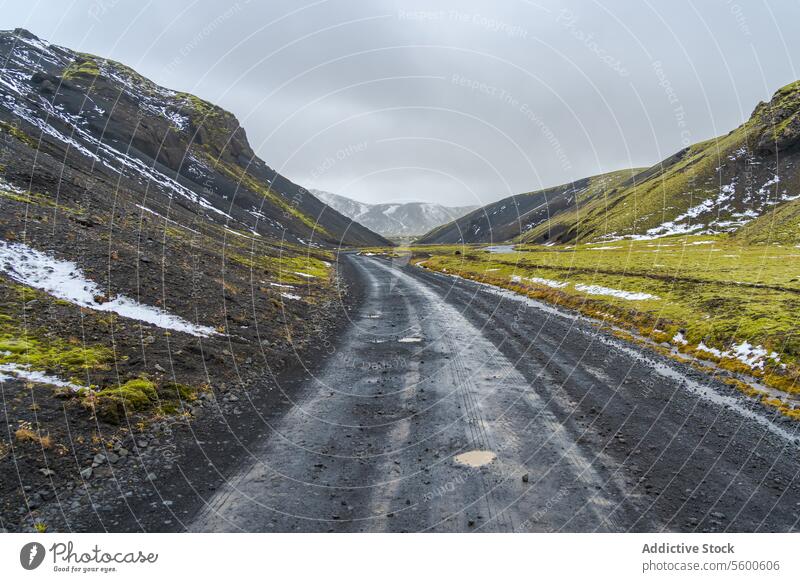 Remote gravel road winding through Icelandic highlands iceland landscape nature desolate remote rugged mountain snow cliff scenic travel adventure tourism