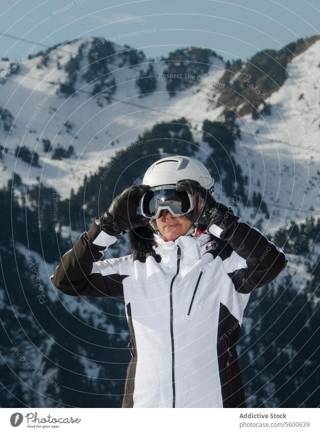 Skier Adjusting Goggles in Swiss Alps Mountainscape skier woman swiss alps snow mountain goggles winter sport ski attire white adjusting landscape peak outdoor
