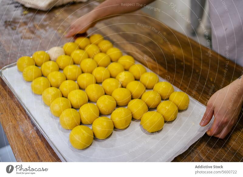 Portrait of yellow dough balls portrait close-up hands lifting turmeric bread bakery tray food flour wheat fresh yeast tasty business production making