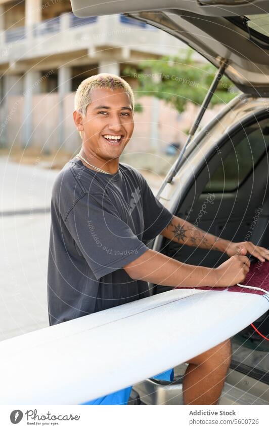 Happy man with surfboard in car on street auto automobile vehicle male transport driver smile confident ethnic service cheerful modern young urban happy serious