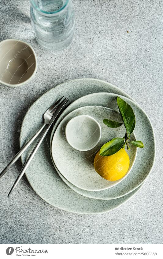 Fresh Lemon on Speckled Ceramic Dinnerware fresh lemon leaves speckled ceramic dinnerware cutlery glassware textured surface vibrant plate bowl kitchen dining