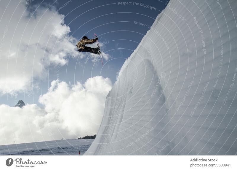 Anonymous man jumping with snowboard on Swiss Alps against blue cloudy sky anonymous snowboarder mountain blue sky sunlight vacation warm clothes peak full body