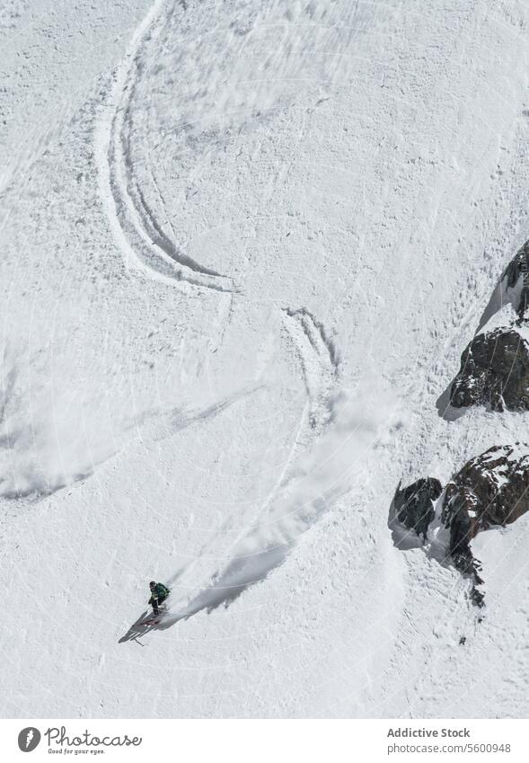 High angle of unrecognizable person skiing on snow mountain during vacation at Swiss Alps during sunny day skier enjoy winter covering swiss alps from above