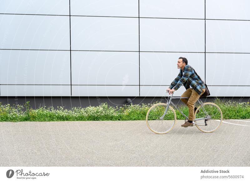 Young man with bicycle on street ride bike urban city building transport vehicle style modern wall contemporary trendy walk male casual town outdoors full body