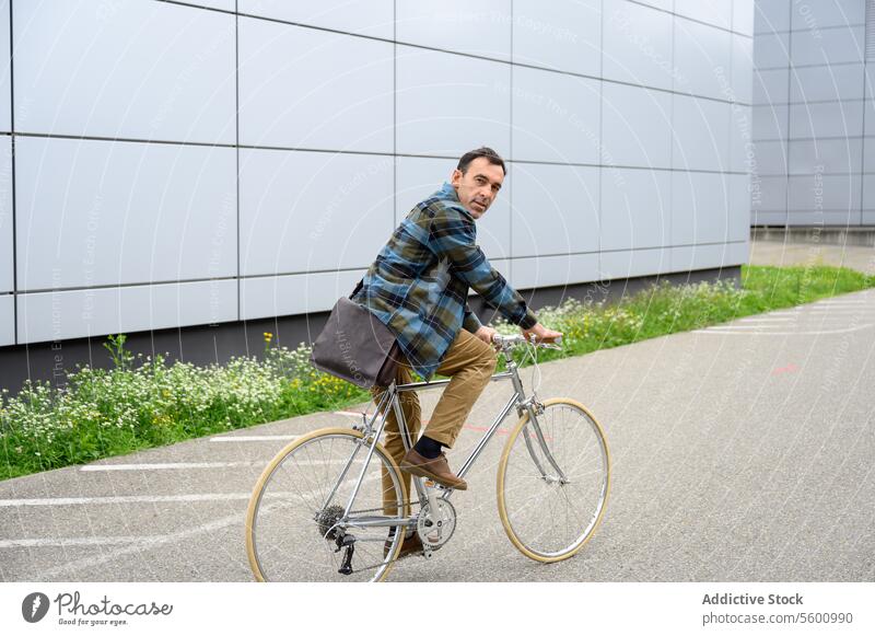 Young man riding bicycle bike ride street city urban woman female style building modern cyclist vehicle transport casual contemporary town cheerful young
