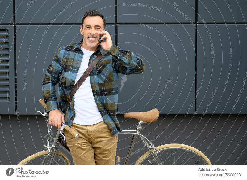 Cheerful man with bicycle talking on phone male smartphone street hipster style casual bike city handsome urban beard modern smile building businessman call