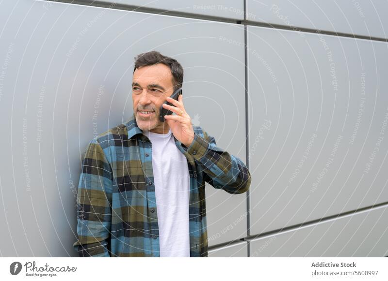 Smiling man talking on smartphone male conversation speak phone call gadget communicate using device smile cheerful chat mobile happy casual modern guy