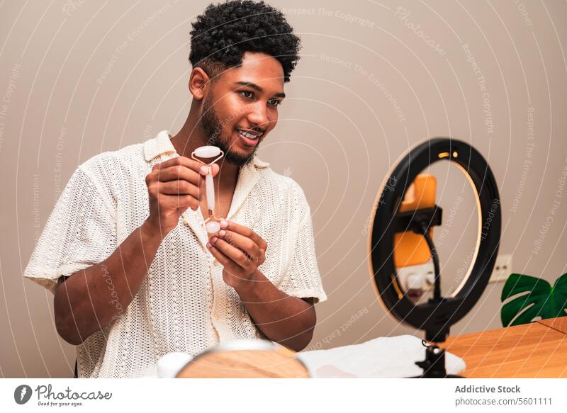 latin man engaged in daily grooming routine with facial roller skincare mirror smiling self-care young beauty health wellness lifestyle personal hygiene