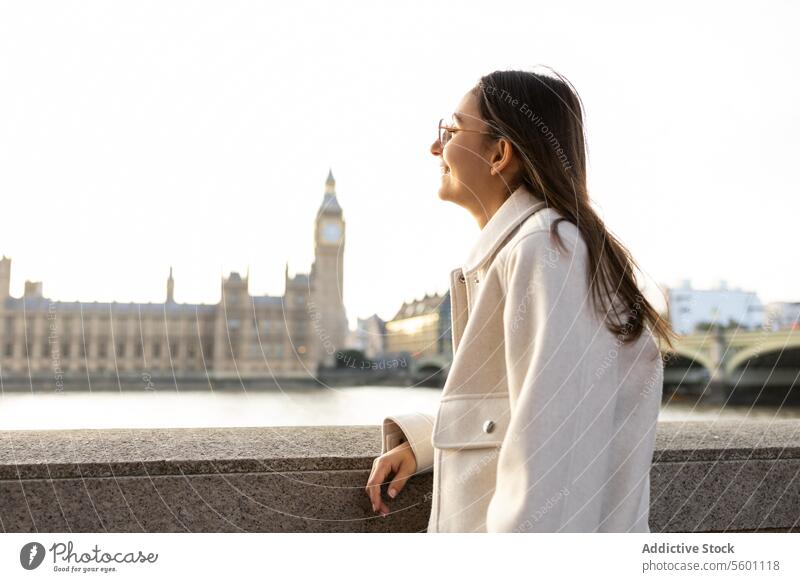 Woman enjoying the view of London's iconic skyline woman london landmark houses of parliament big ben bridge railing profile young gazing historic leaning side