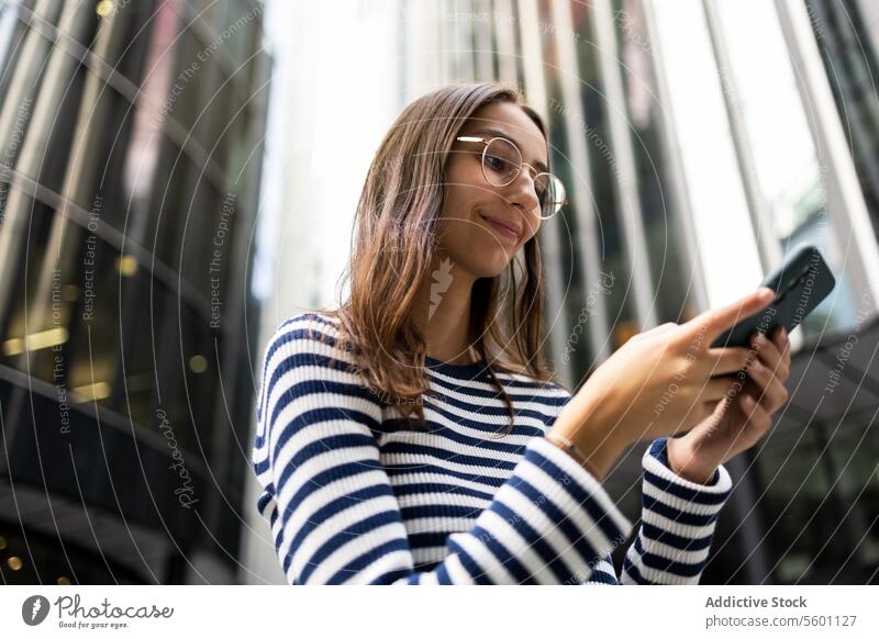 Young Woman Using Smartphone in Urban London Setting woman smartphone london urban building smiling technology communication city modern architecture young