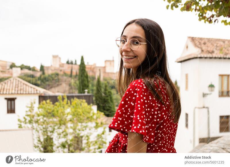 Smiling tourist standing while looking at camera against Alcazaba in town alcazaba woman historic tree side view casual attire explore travel lifestyle leisure