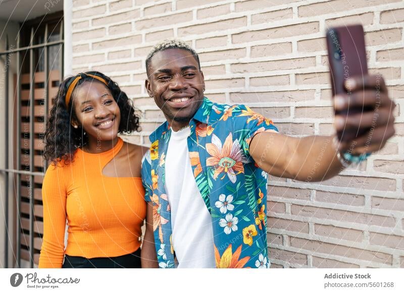 Friends taking a selfie in the street young black friends couple smiling smartphone camera happy lifestyle outdoor mobile technology urban casual man woman