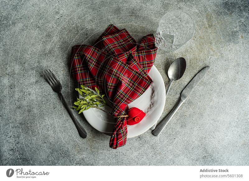 Valentine's Day table with heart decor placed on concrete surface at kitchen table Plate cutlery spoon napkin red tartan decoration day love dinner knife fork
