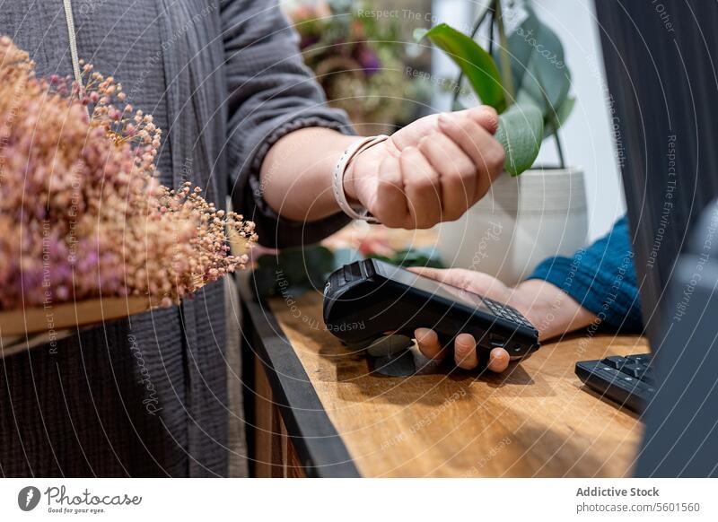 Contactless payment with smartwatch at store checkout contactless technology transaction customer flower cashier close-up financial purchase retail shop