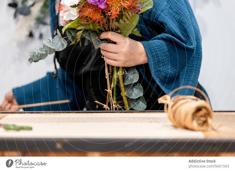 Anonymous person crafting a bouquet with flowers florist arrangement workbench hand design floral horticulture hobby profession creative nature plant stem leaf