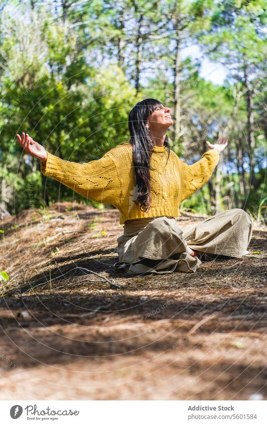 Woman sitting on the woods with arms opened while looking to the sky like thanking God. Vertical shot. Human Hand asana balance breathe breathing calm calmness